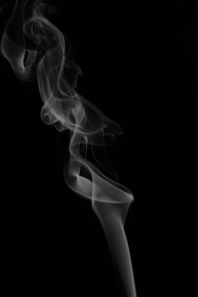 A thin line of white smoke rising in the dark
